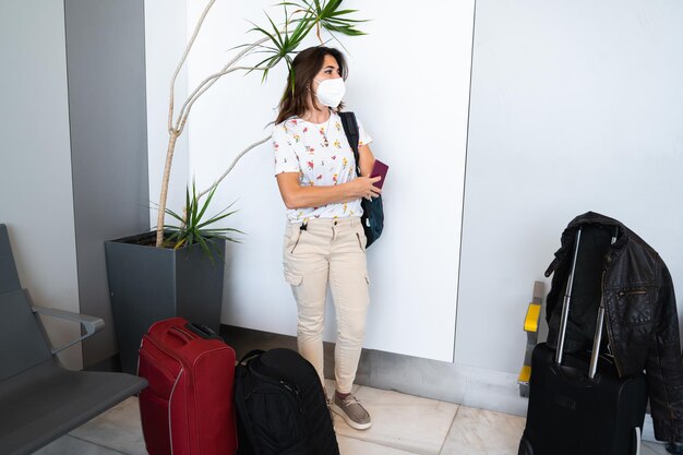 Femme debout avec masque protecteur attendant dans le salon de l'aéroport