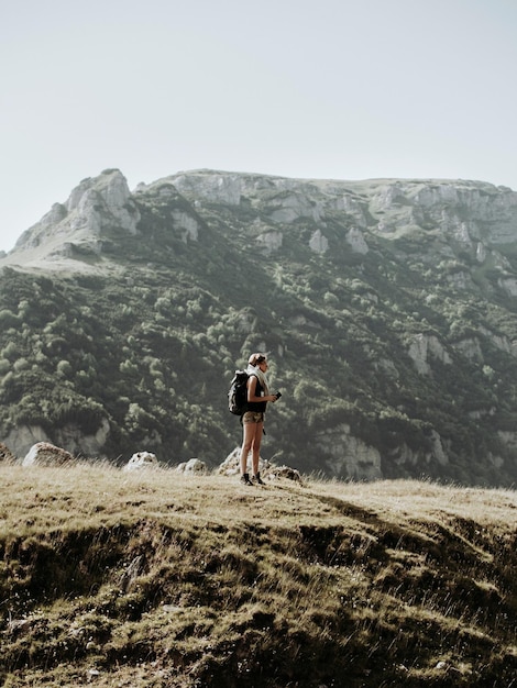 Une femme debout sur une montagne contre un ciel clair