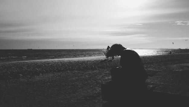 Une femme debout sur la plage contre le ciel