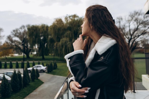 Photo femme debout en plein air sur un balcon en verre confiant par temps froid et venteux automne printemps