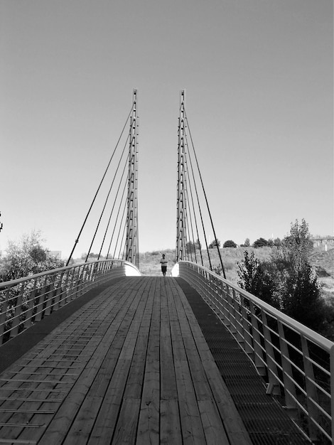 Photo une femme debout sur un pont suspendu contre un ciel dégagé