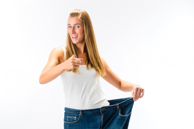 Femme debout et portant un pantalon trop grand après avoir perdu du poids