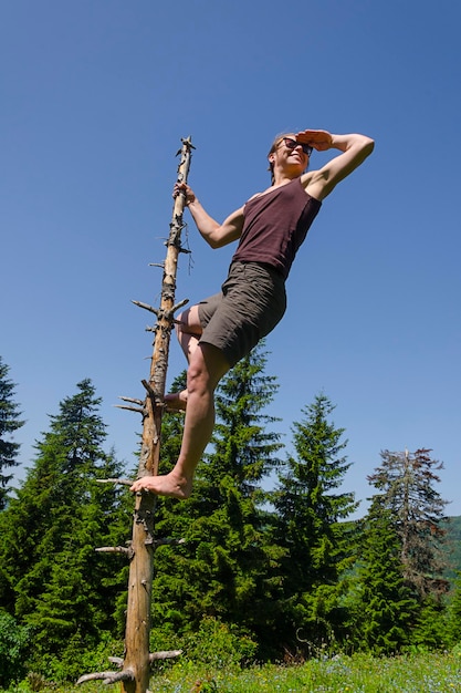 Une femme debout sur un poteau de bois contre un ciel bleu clair.