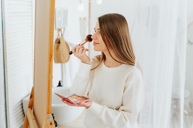 Femme debout près du miroir et maquillant