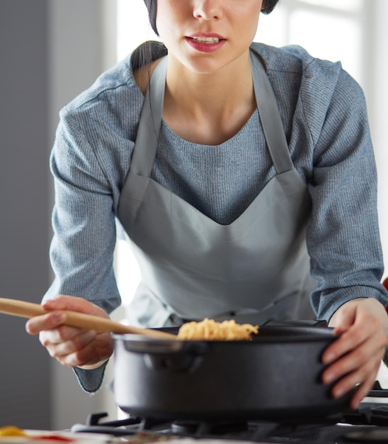 Femme debout près du poêle dans la cuisine cuisinant et sentant les bons arômes