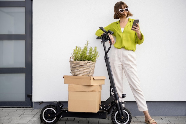 Femme debout près de scooter avec colis et pot de fleurs