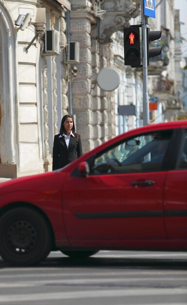 Une femme debout près d'une voiture dans la rue de la ville