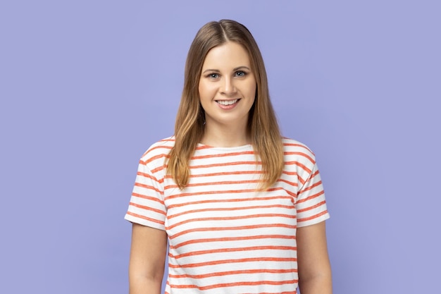 Femme debout regardant la caméra avec une expression faciale heureuse étant de bonne humeur