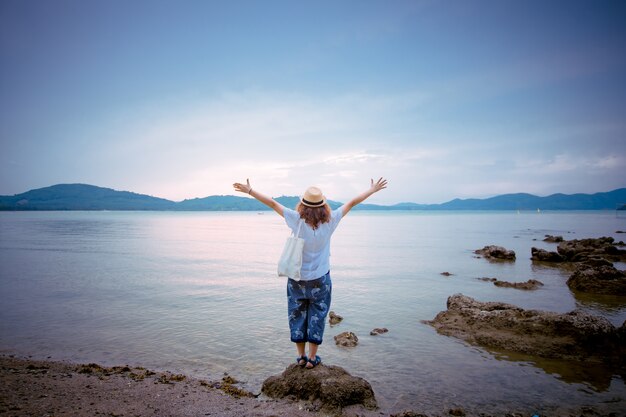 femme debout sur un rocher à la mer avec la montagne.