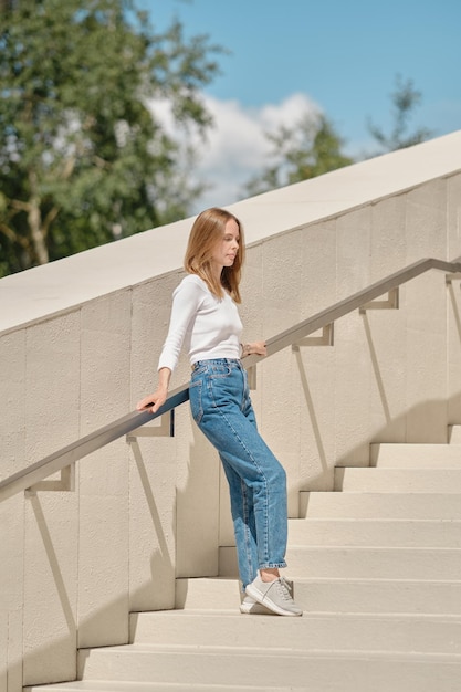 Femme debout avec son dos contre la rambarde des escaliers écartant les bras