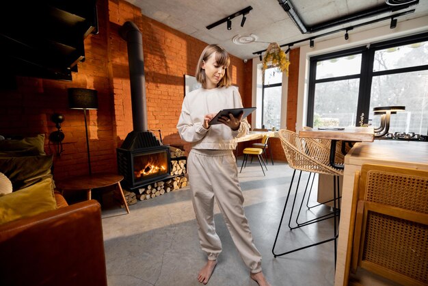 Femme debout avec une tablette numérique dans un salon confortable de style loft