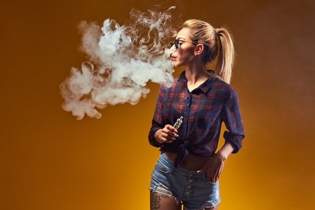 Femme debout et vaping en studio