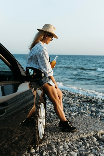 Photo femme debout en voiture avec une bouteille de jus