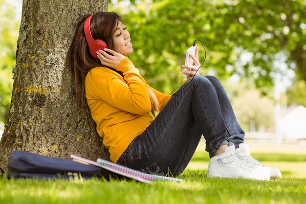 Femme décontractée, appréciant la musique dans le parc