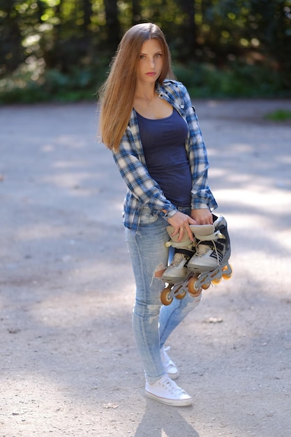 La femme décontractée aux cheveux longs tient des patins à roulettes.