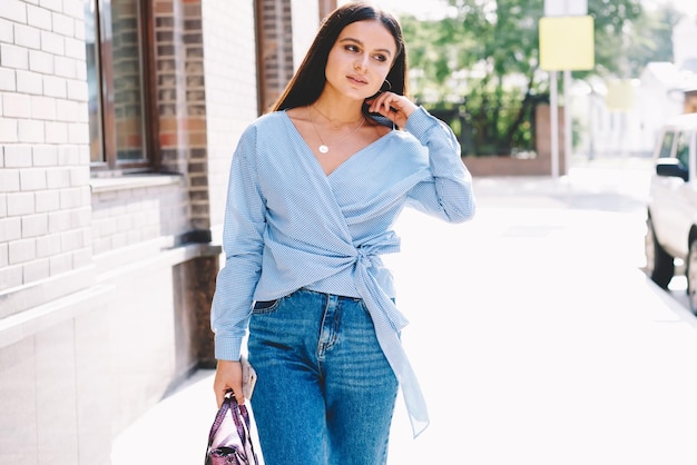 Femme décontractée descendant la rue vers le bureau de travail belle fille hipster de 20 ans en chemise bleue