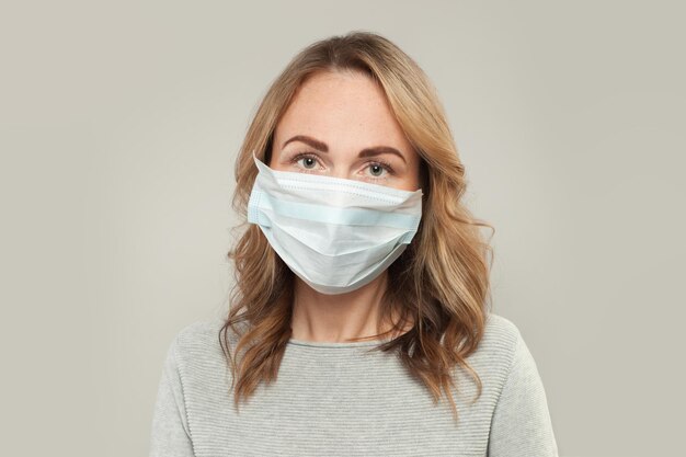 Femme décontractée avec un masque de protection médicale sur blanc