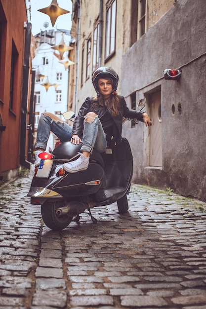 Photo femme décontractée sur moto scooter dans la rue de la vieille ville.