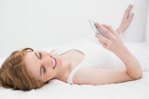 Femme décontractée en regardant téléphone portable au lit