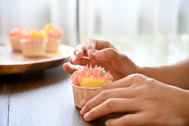 Femme décorant son petit gâteau fait maison dans la cuisine