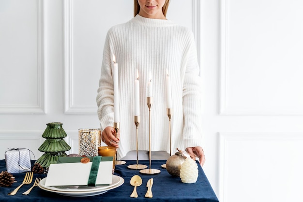 Femme décorant une table à manger de Noël avec des bougies