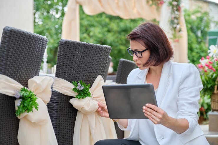 Femme décoratrice professionnelle avec tablette numérique travaillant à l'extérieur cérémonie de décoration