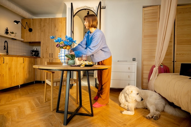 Femme décore une table à manger avec des fleurs dans un vase