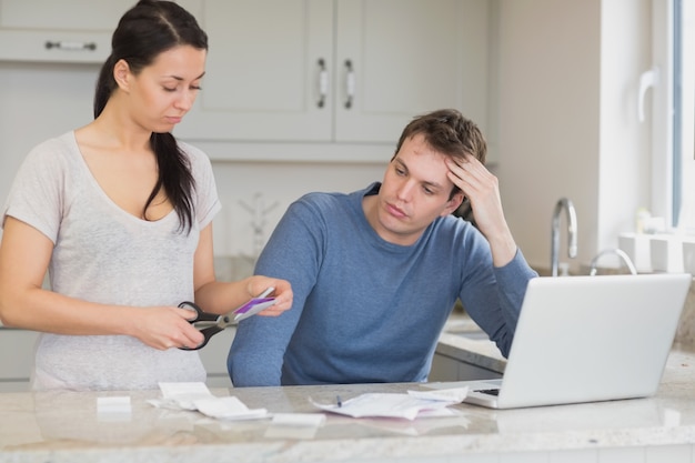 Femme découpant la carte de crédit avec le mari en regardant