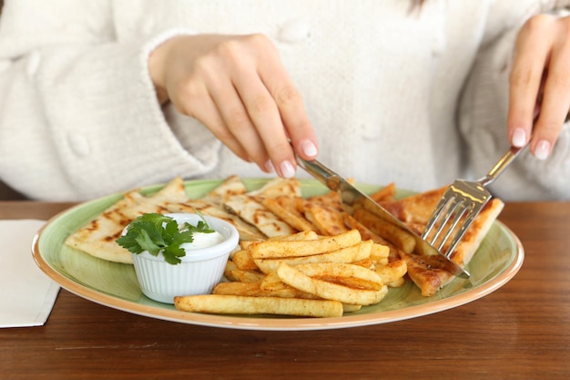 Une femme découpe une assiette de nourriture avec un couteau et une fourchette.