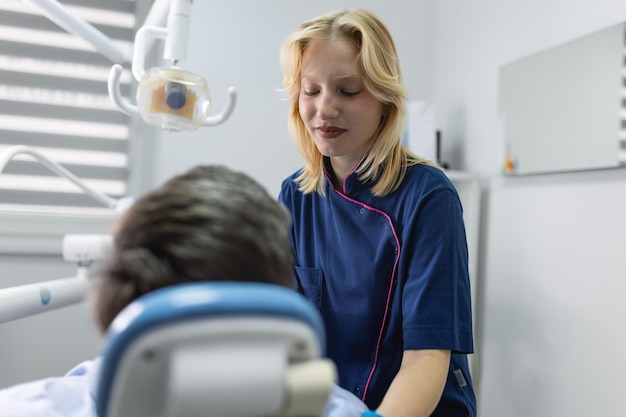 Femme dentiste dans un cabinet dentaire parlant avec le patient et se préparant au traitement