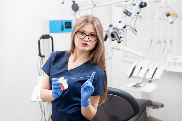 Femme dentiste avec du fil dentaire dans la clinique dentaire