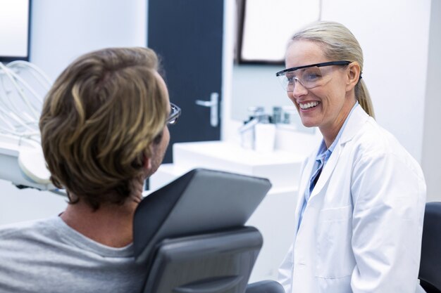 Femme dentiste interagissant avec un patient masculin