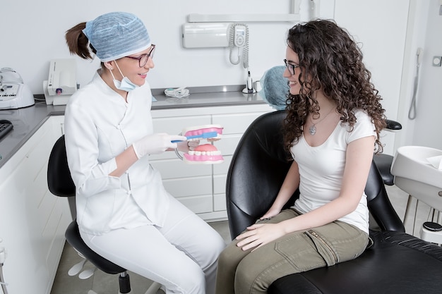 Femme dentiste montrant la technique de brossage des dents à un client