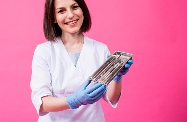 Une femme dentiste ouvre un paquet d'instruments dentaires stériles