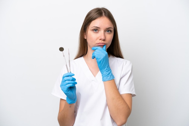 Femme dentiste tenant des outils isolés sur fond blanc pensant