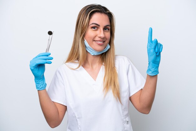 Femme dentiste tenant des outils isolés sur fond blanc pointant vers le haut une excellente idée