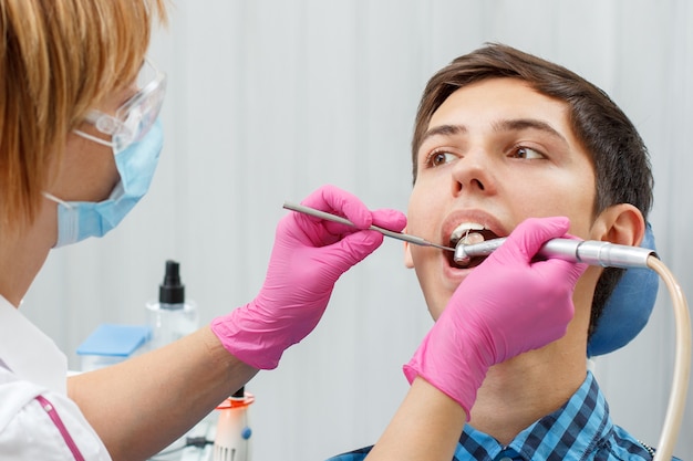 Une femme dentiste traite une dent de patient dans un cabinet dentaire en mettant l'accent sur la bouche du patient. Dentisterie