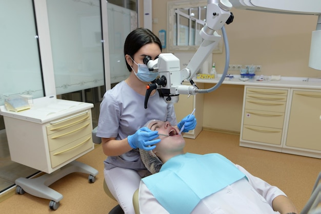 Femme dentiste traite les dents du patient sous microscopeConcept de dentisterie