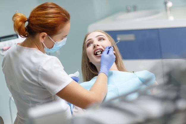 Femme dentiste vérifiant les dents du patient