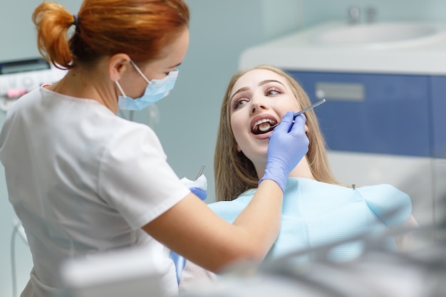 Femme dentiste vérifiant les dents du patient