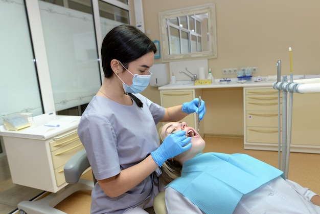 Une femme dentiste vérifie les dents d'une jeune patiente Le concept de soins dentaires dentaires