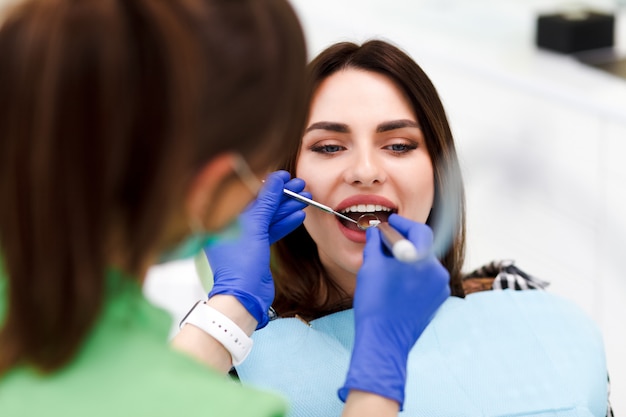 Femme à la dentisterie Le dentiste traite les dents de sa jolie patiente. Le médecin dentaire perce les dents du patient