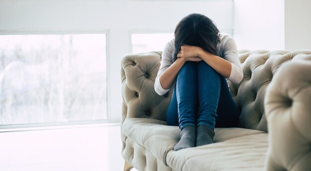 Femme déprimée avec une coupe courte qui pleure en touchant son visage. Fille qui crie les yeux fermés à cause de sa maladie mentale.