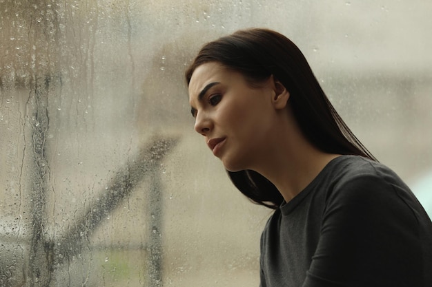 Femme déprimée près de la fenêtre sur l'espace jour de pluie pour le texte