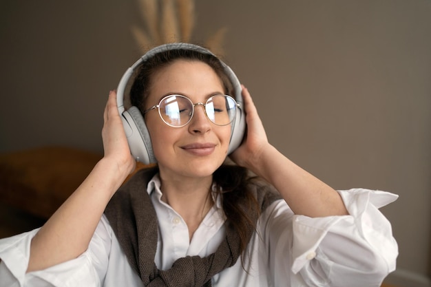 Une femme designer avec des lunettes écoute de la musique avec des écouteurs