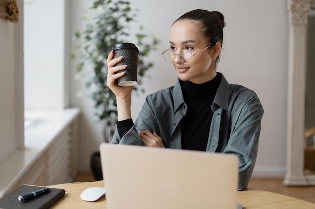 Une femme designer de pause-café utilise un ordinateur portable dans un rapport de bureau sur les finances et le budget de l'entreprise f