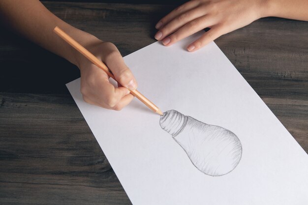 La femme dessine une ampoule sur papier