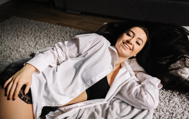 Femme détendue allongée sur le sol à l'intérieur et souriant