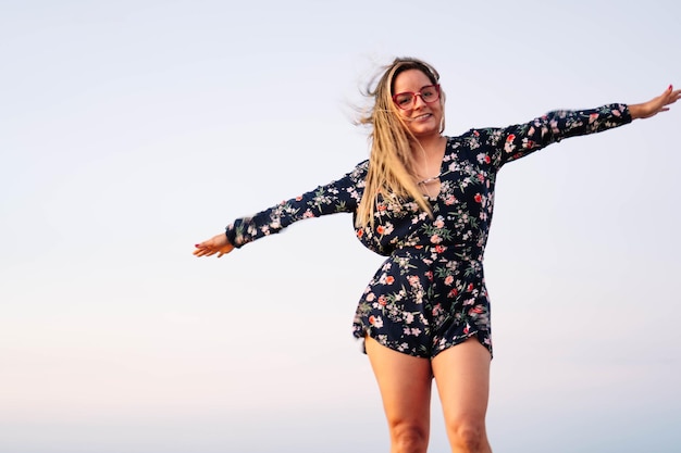 Femme détendue aux cheveux blonds souriant à bras ouverts aux beaux jours