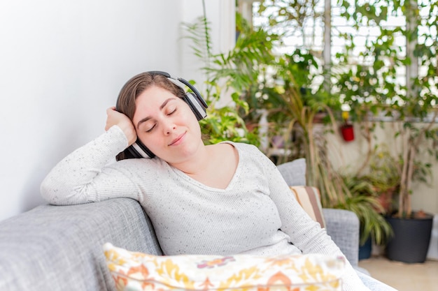 Femme détendue écoutant de la musique avec des écouteurs à la maison